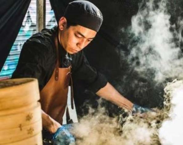 Chef in a steamy kitchen with bamboo steamers